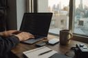 コードが表示されたノートパソコンのある、窓際の作業机