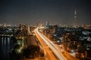 夜の街を貫く道路の光跡と、街明かり・電波塔