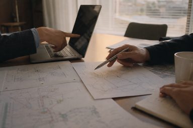 ノートパソコンと回線図の資料を前にした打ち合わせ